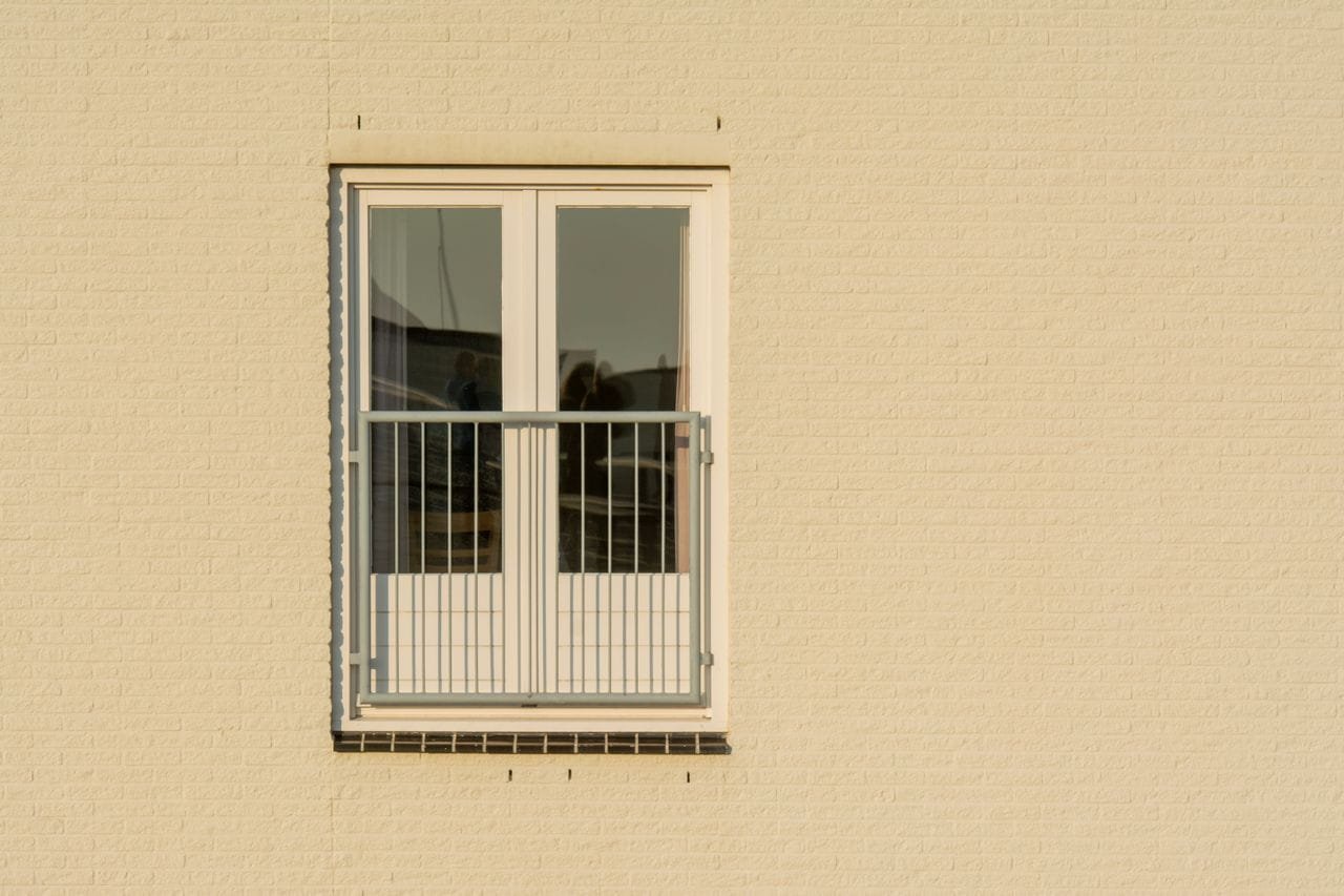 Raam met balkon in een beige gevel